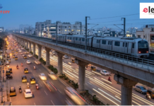Namma Metro Crosses 100 km as Pink Line Gets Safety Clearance Generic elevated modern metro train running on a concrete viaduct over a busy Indian road during blue hour with traffic light trails.